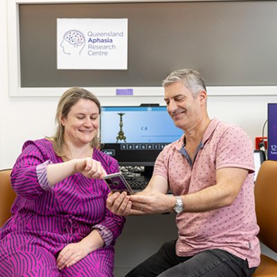 QARC researcher Jessica Campbell showing a person with aphasia an app on a phone.